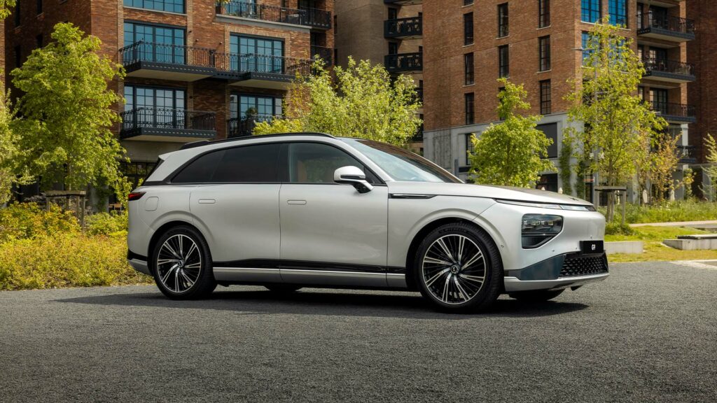 En vit SUV parkerad framför ett byggnad. (AI text)