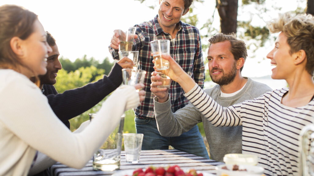 En grupp vänner skålar vid en picnic-bord (AI text)