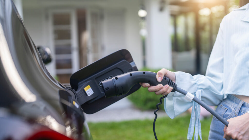 En kvinna laddar sin bil hemma. (AI text)