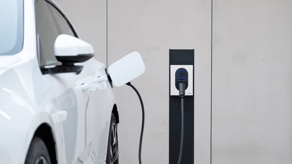 En vit bil är uppkopplad till en el-laddstation. (AI text)