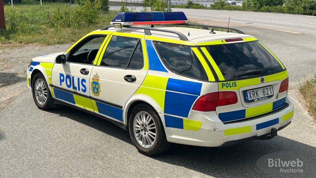 En polisbil parkerad vid en väg. (AI text)