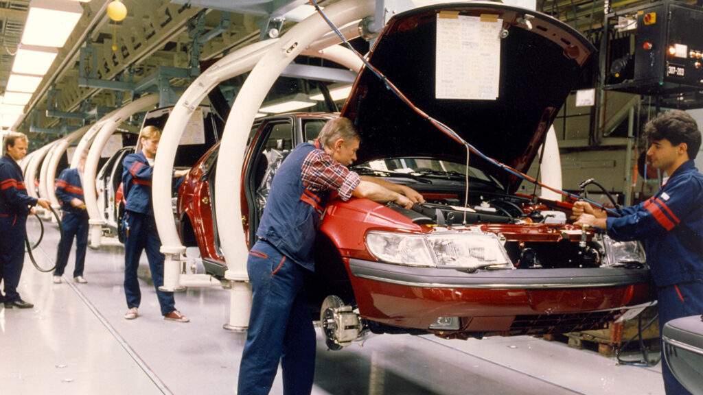 En bilmonteringslinje där personer arbetar på bilar. (AI text)