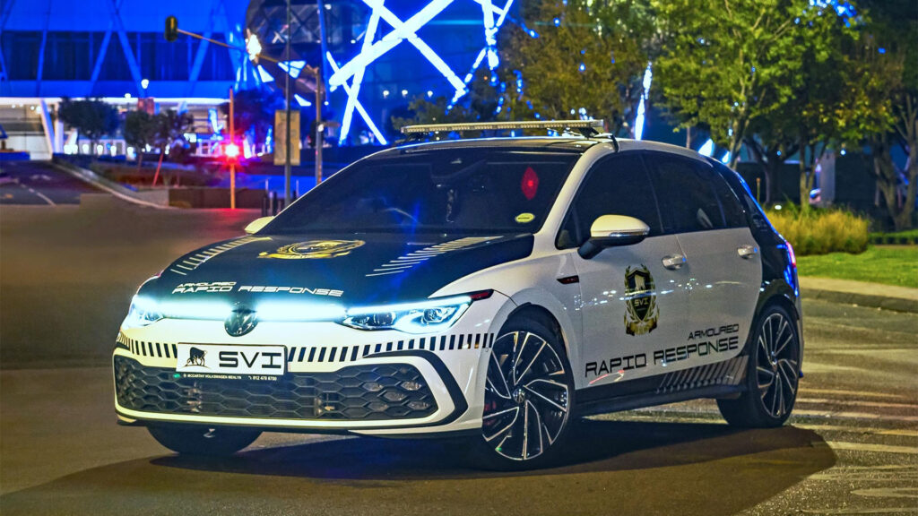 En polisbil kör nedför en stadsgata på natten. (AI text)