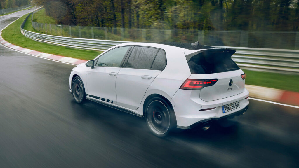En vit Volkswagen Golf GTI kör på en blöt bana. (AI text)