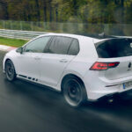 En vit Volkswagen Golf GTI kör på en blöt bana. (AI text)