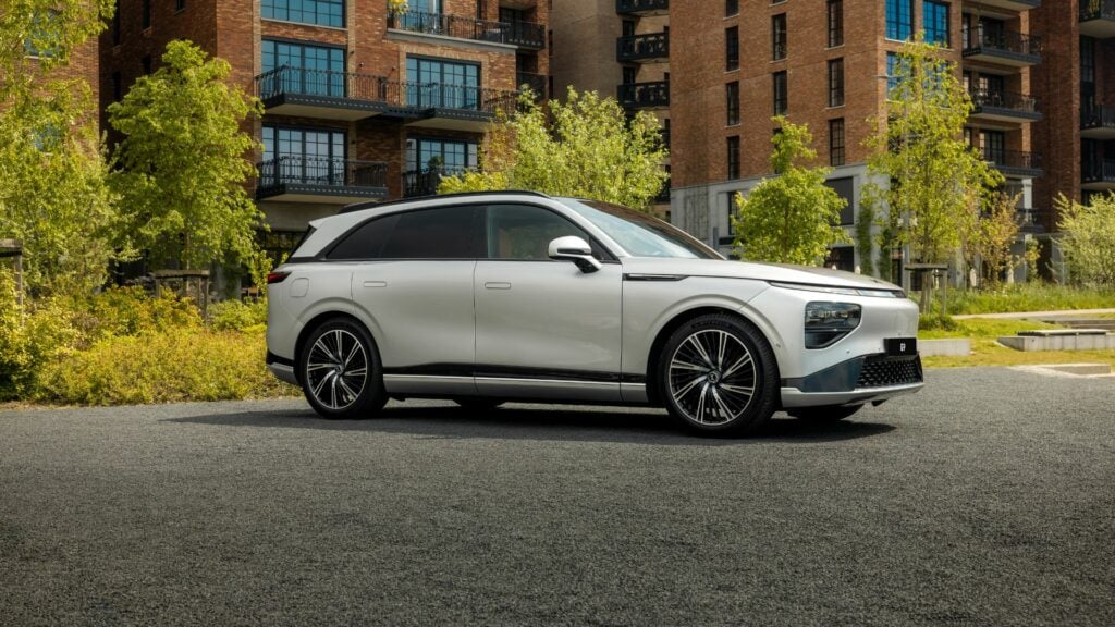 En vit SUV parkerad framför ett byggnad. (AI text)