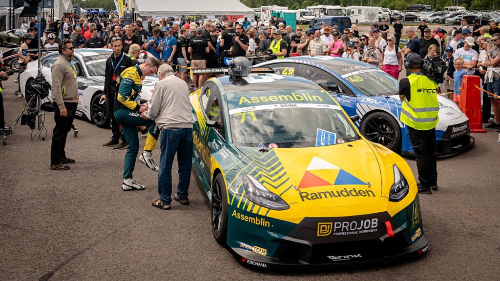 En skara människor samlades runt en racebil. (AI text)