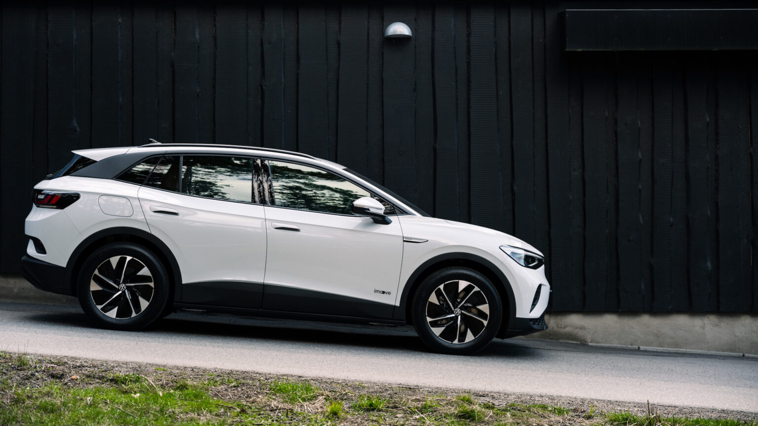 En vit SUV parkerad på en svart vägg. (AI text)