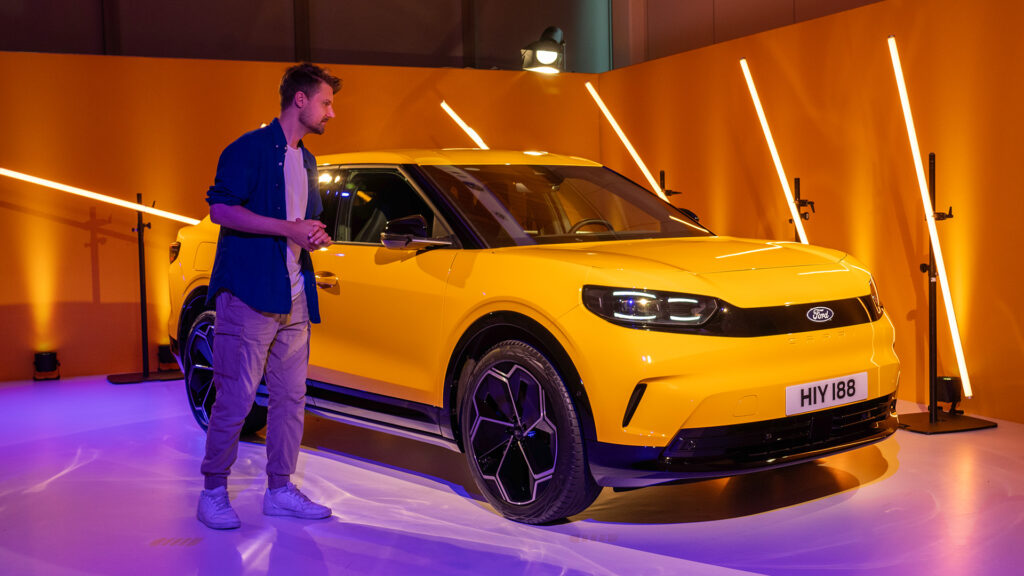 En man står bredvid en gul SUV. (AI text)