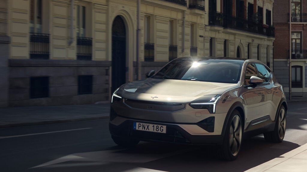 En silverfärgad SUV kör nerför en stadsgata. (AI text)