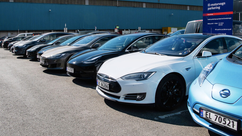En rad parkerade Tesla Model S-elbilar framför en fabrik. (AI text)