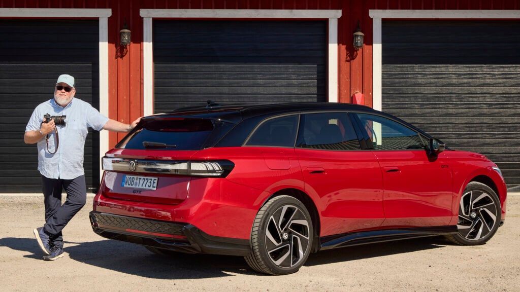 En man står bredvid en röd bil. (AI text)