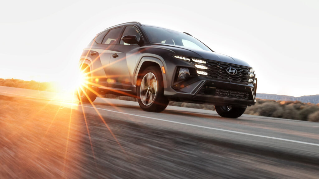 en svart SUV kör nedför en väg vid solnedgången (AI text)