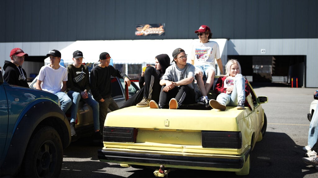 En grupp personer står bredvid en bil. (AI text)