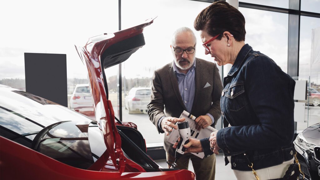 En kvinna och man tittar på en bil i en showrum. (AI text)