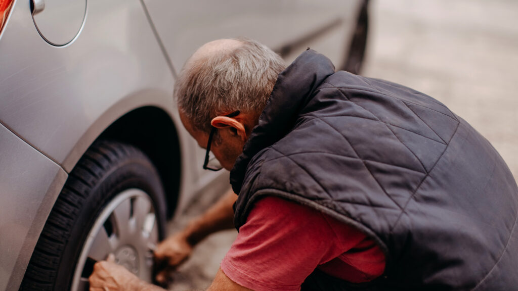 En man monterar en däck på sin bil. (AI text)