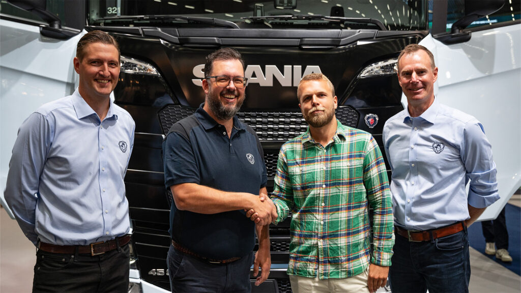 Män står sammanlagt framför en lastbil. (AI text)