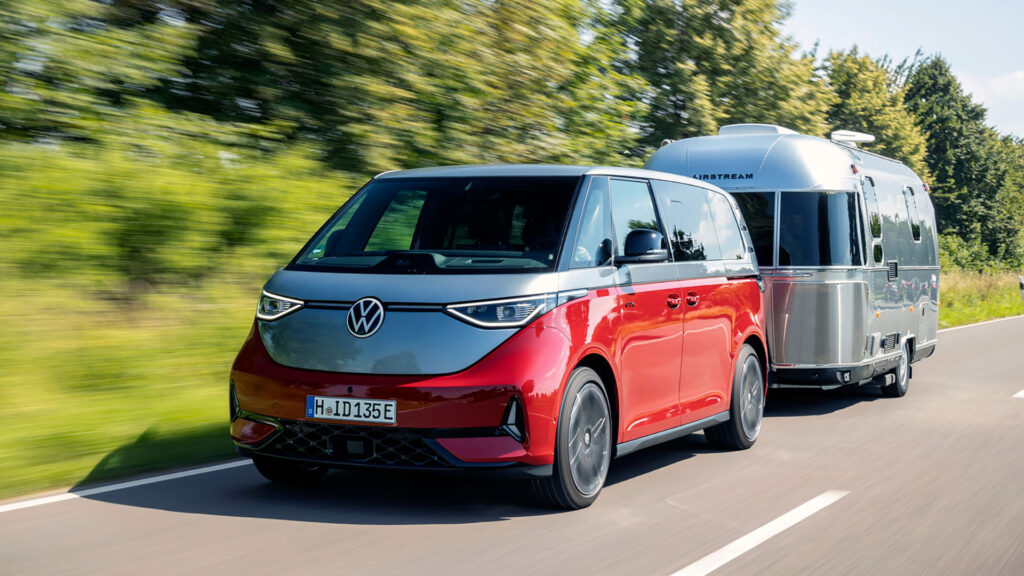 En röd VW-bus som draftar en campingvagn längs en landsväg. (AI text)