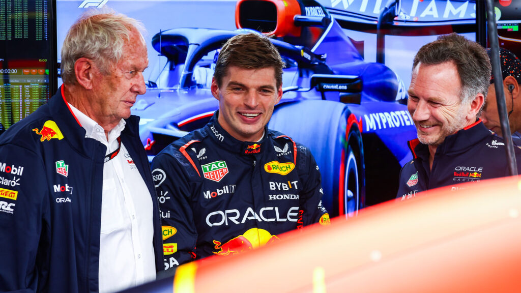 Personer står bredvid en Red Bull-racebil. (AI text)