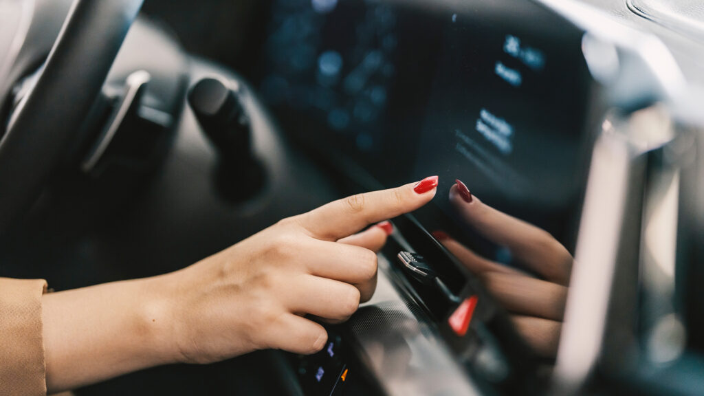 En kvinna kör en bil med en pekskärm. (AI text)