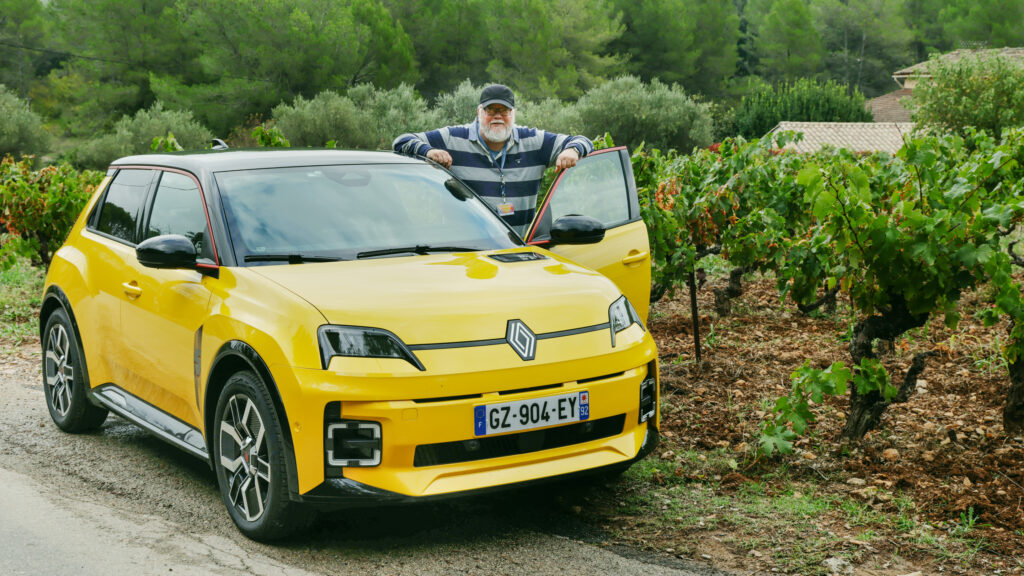 En man står bredvid en gul VW EC3 i en vingård. (AI text)