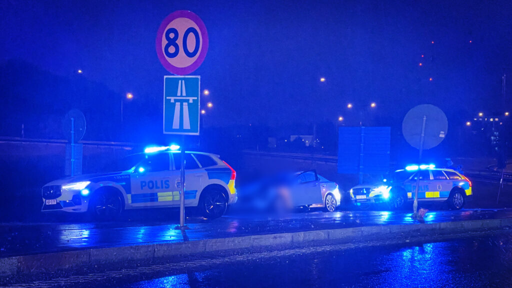 Två polisbilar har stoppat en silverfärgad Lexus intill motorvägen.