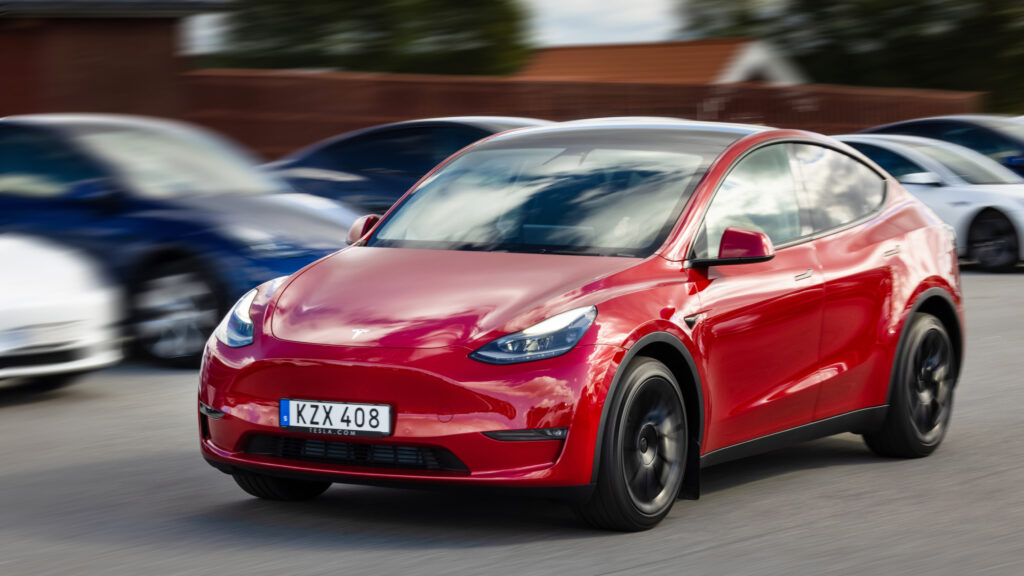 Tesla Model Y kör i en parkeringsplats. (AI text)