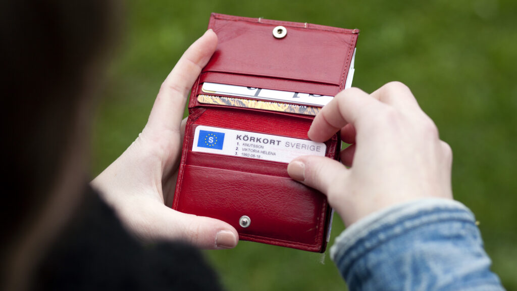 En kvinna håller en väska och ett mobiltelefon. (AI text)