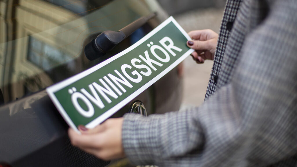 En man håller upp en skylt som säger "Övingsborg". (AI text)