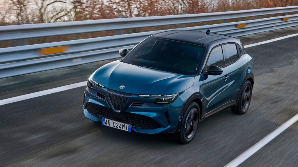 En blå Alfa Romeo-territäckvagn kör nerför en väg. (AI text)