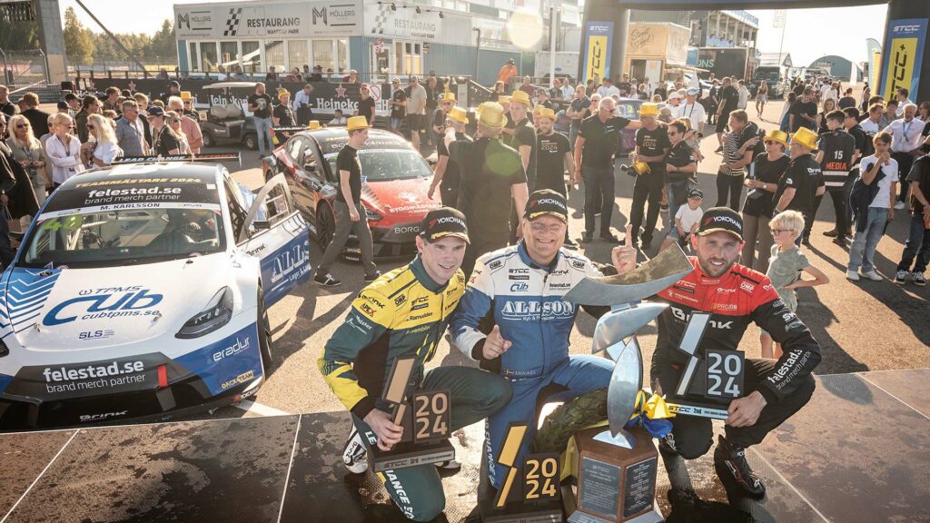 En grupp personer står på en podiet med pokaler. (AI text)