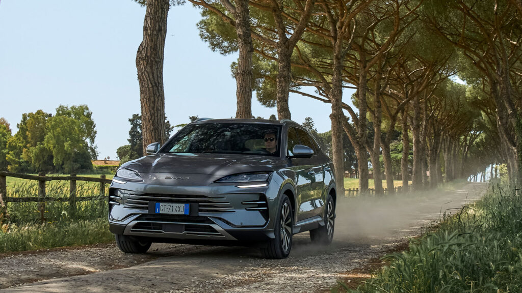 En silverfärgad SUV kör nerför en grusväg. (AI text)