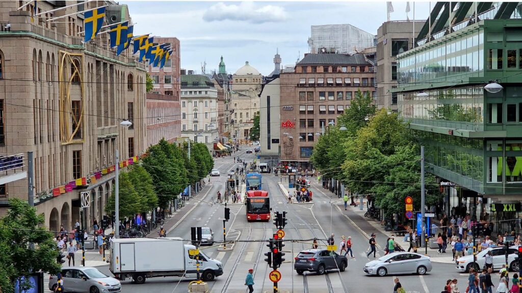 En stadsgata med bilar och folk. (AI text)