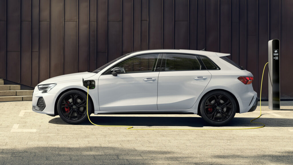 Vit Audi A3 ansluten till en laddstolpe.