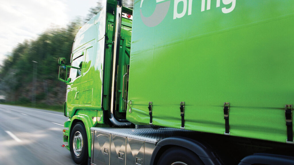 En grön lastbil kör ner en väg. (AI text)