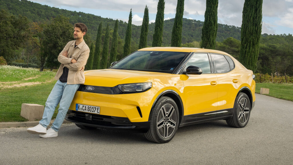 En man står bredvid en gul SUV. (AI text)