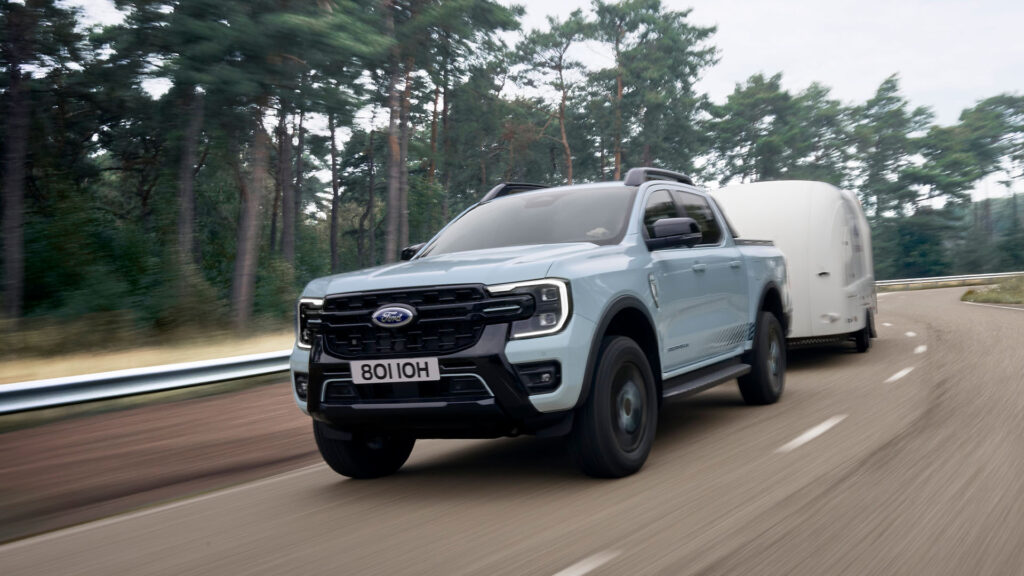 En Ford Explorer med turbogasmotor kör längs en landsväg med en släp bakom sig. (AI text)
