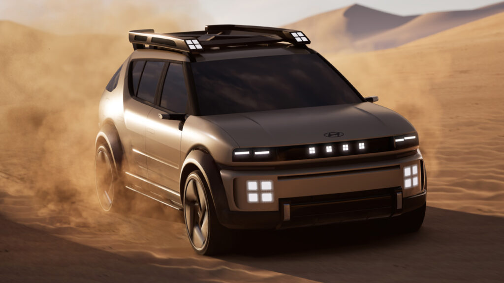 Hyundai Initium kör i öknen med sanddyner i bakgrunden.