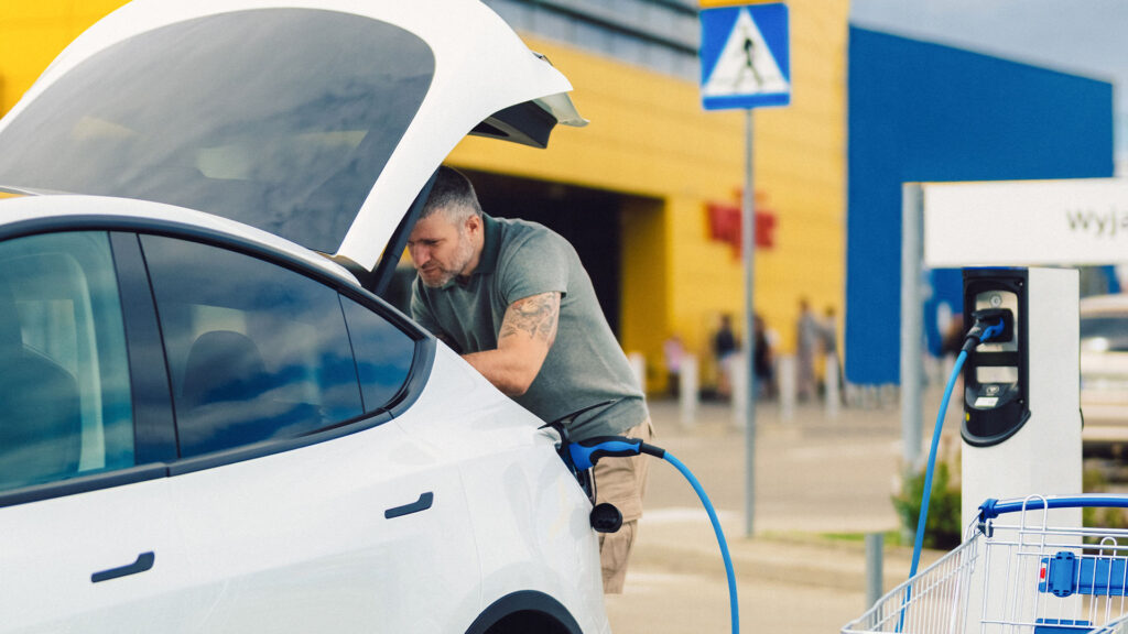 En man laddar sin bil på en laddstation. (AI text)