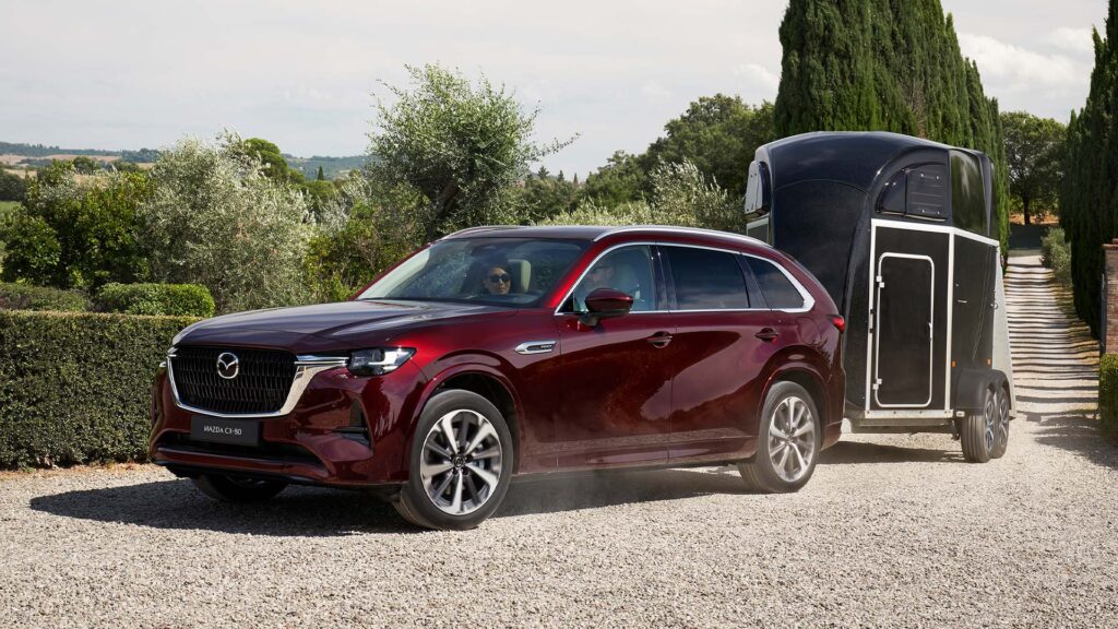 Vinröd Mazda CX-80 drar hästtransport.