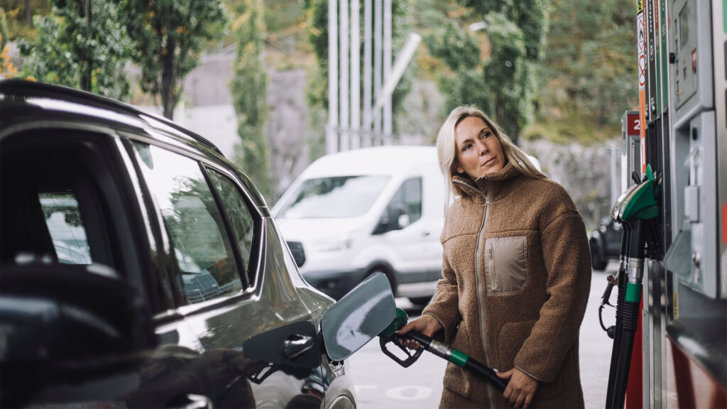 En kvinna tankar sin bil på en bensinstation. (AI text)