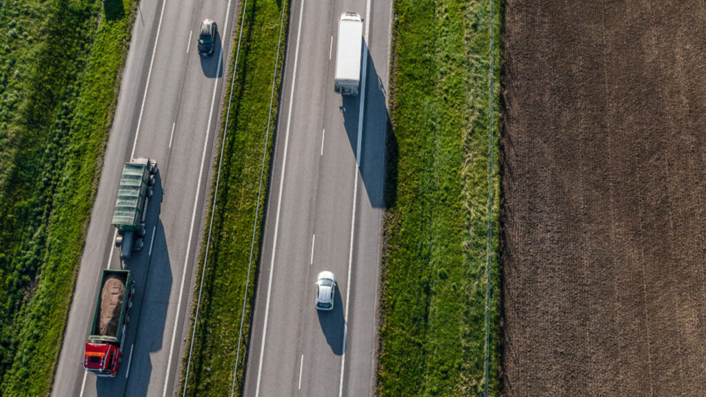 Övervakningsbild av en väg där lastbilar och bilar kör på den. (AI text)