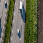 Övervakningsbild av en väg där lastbilar och bilar kör på den. (AI text)