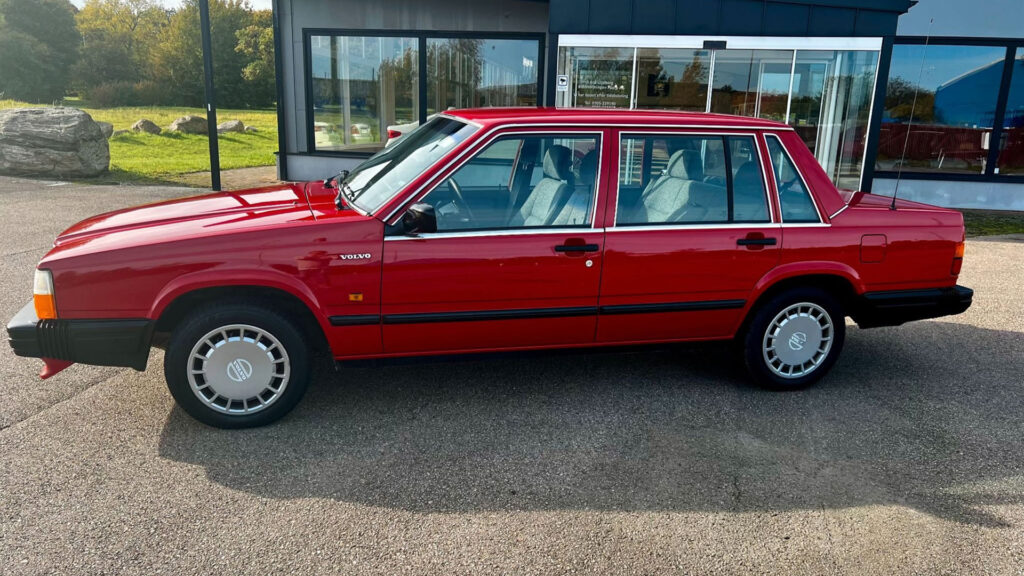 En röd bil parkerad framför ett byggnad. (AI text)