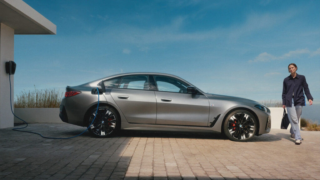 BMW står och laddar med en kvinna gåendes till höger i bild.