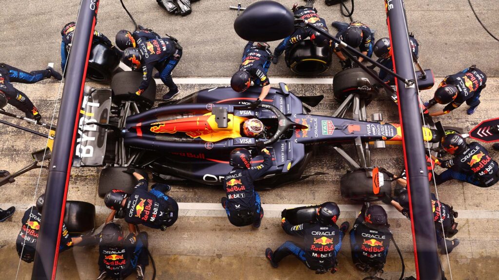 Red Bull F1-bil ovanifrån med mekaniker kring bilen. Red Bull F1-bil på banan, exempel på en dyr Formel 1-bil och dess kostnader.