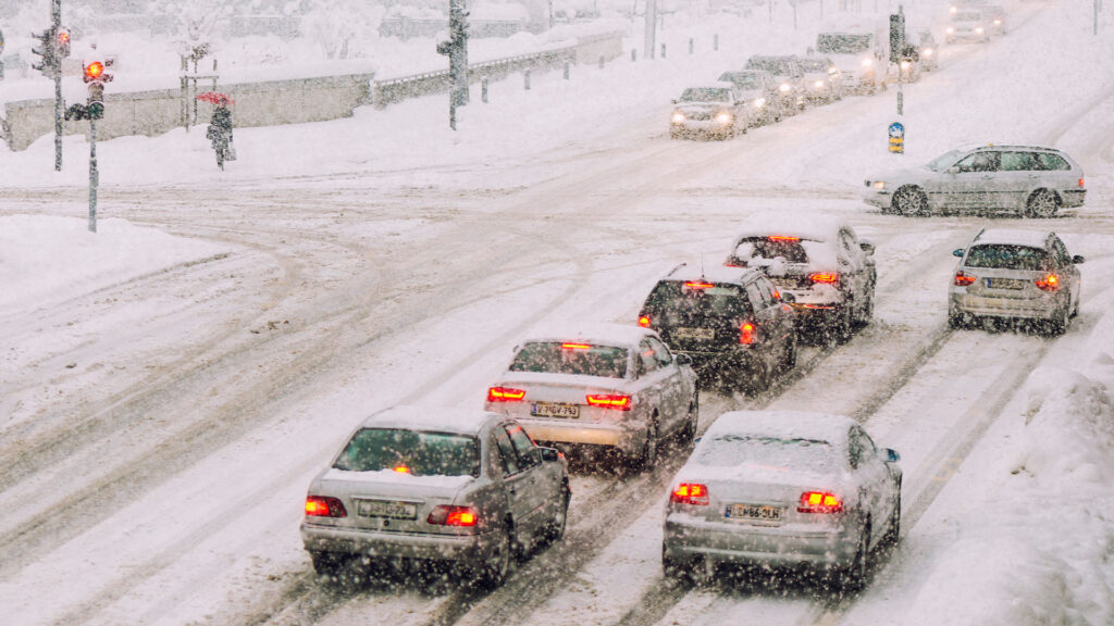 Snöig väg med bilar i korsning.