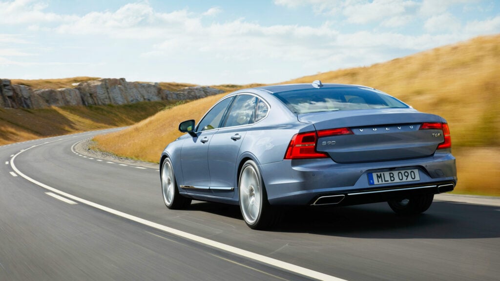 Ljusblå Volvo S90 snett bakifrån på landsväg.