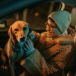 Par sitter med sin hund i en parkerad bil på natten.