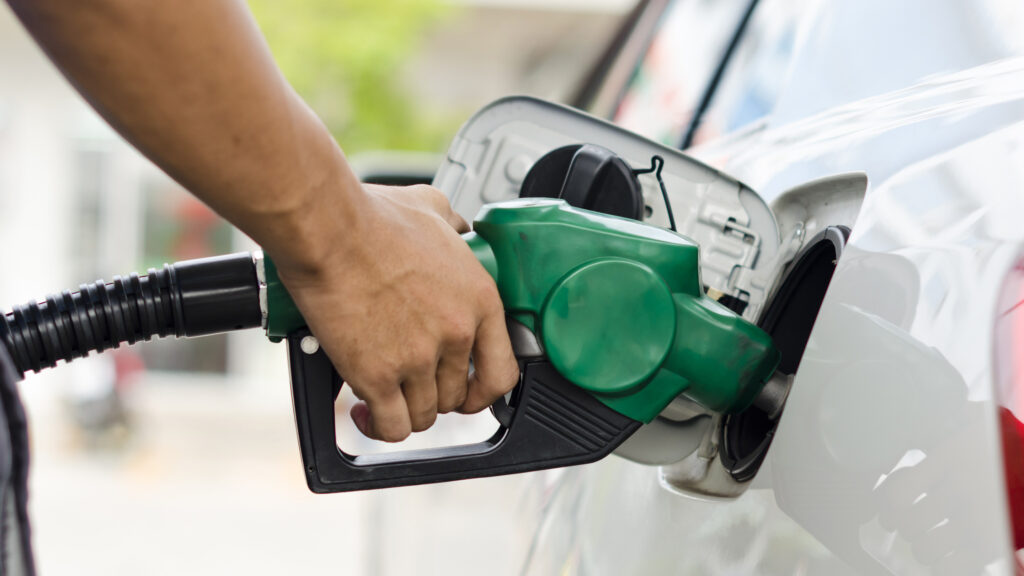 Vit bil tankas med bensin.